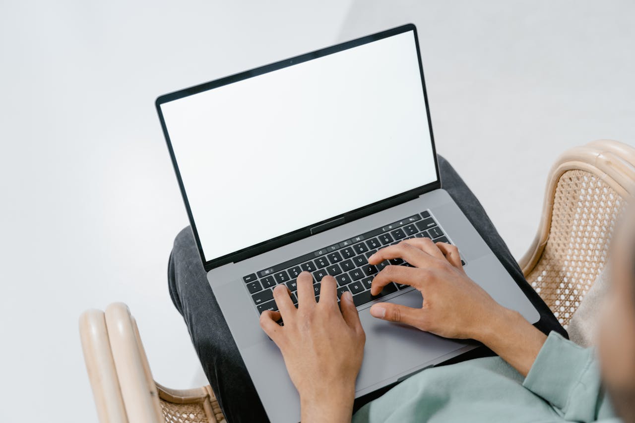 Close-up of hands typing on a laptop with a blank screen, ideal for mockups.